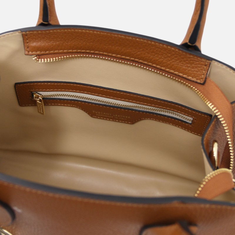 Inside view of a brown leather handbag with beige lining, showing a zippered interior pocket and a small tag reading 'Tuscany Leather' on a leather strip.