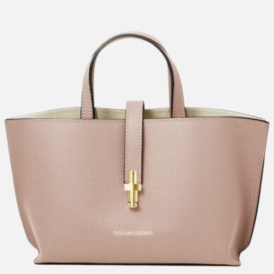 Pink pebble-grain leather tote with two short handles and a central gold clasp closure at the front pocket strap, brand Tuscany Leather visible at bottom.