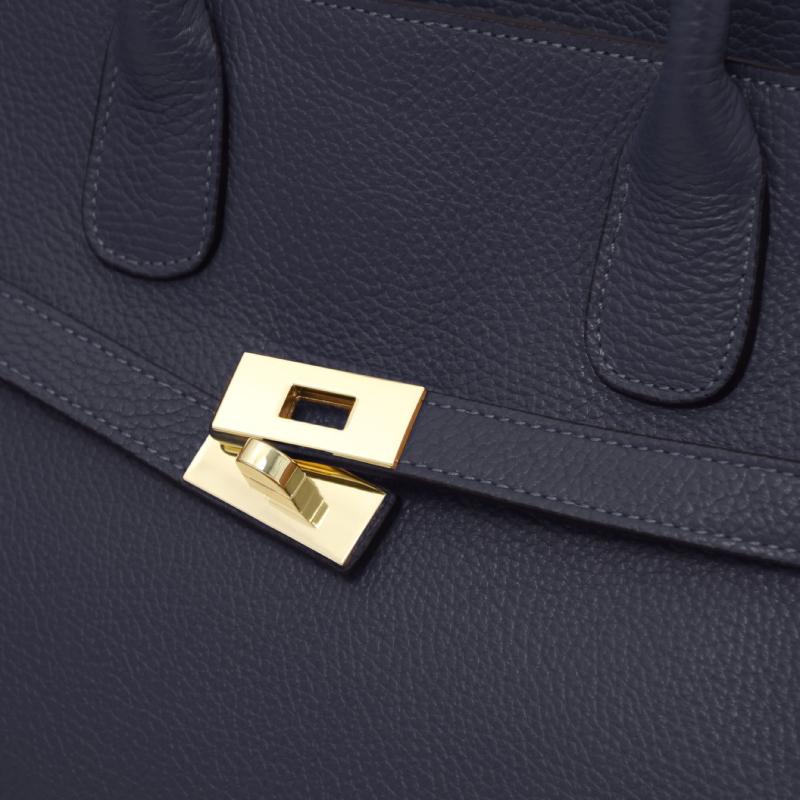 Close-up of a navy blue leather handbag with a gold rectangular turn-lock clasp.