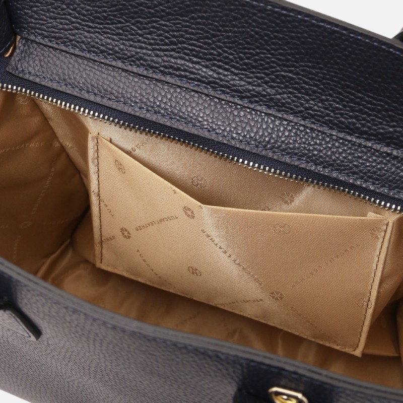 Interior of a navy leather bag with tan fabric lining and a zippered top edge viewed from above.