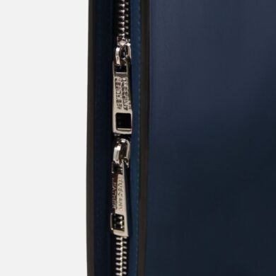 Close-up of a double silver zipper on a dark blue leather bag, with pulls labeled 'Tuscany Leather'.