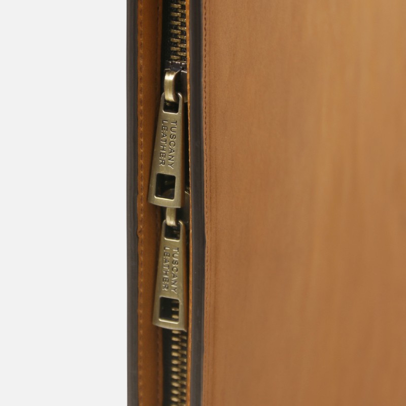 Close-up of two brass zipper pulls on a brown leather bag, partially open, showing the zippers side by side.