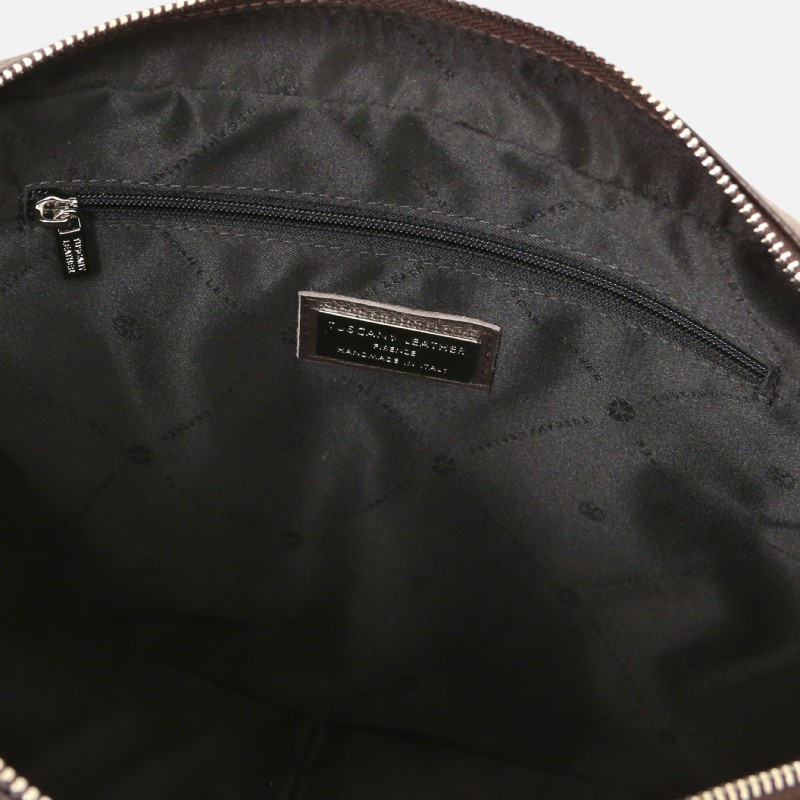 Interior view of a black bag with a zippered inner pocket and a brand label sewn above it center-stage inside the opening.