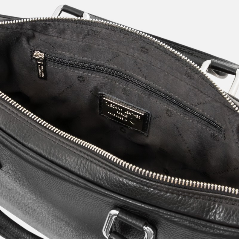 Open black leather handbag interior showing a zippered pocket, brand label, and silver hardware, with white accents at the top.