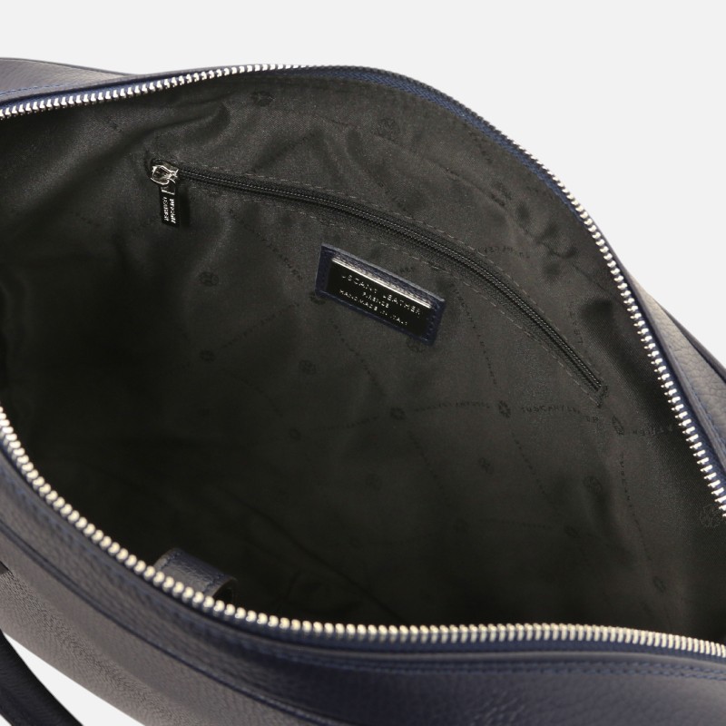 Open navy blue handbag interior showing a zippered inner pocket and a brand label on the lining.