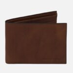 Brown leather bi-fold wallet with visible stitching and a subtle Tuscony Leather branding on the bottom right edge of the front panel