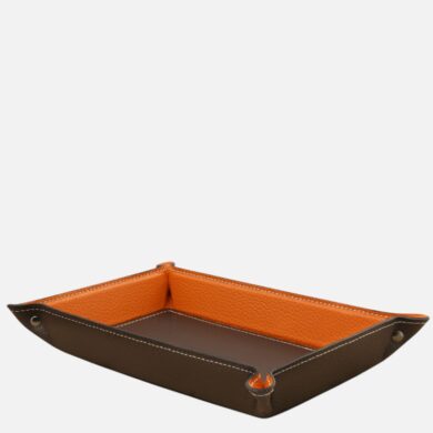 Leather tray with brown exterior and orange interior, raised edges, used for small items like keys and coins.