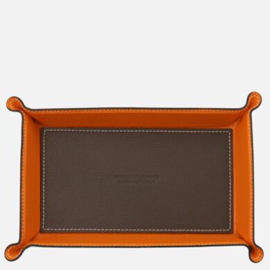 Top-down view of an orange-leather tray with a brown inner panel and white stitching, showing a stylish storage accessory.