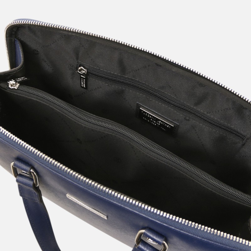 Open blue handbag showing interior with two zippered pockets and a brand label on the lining