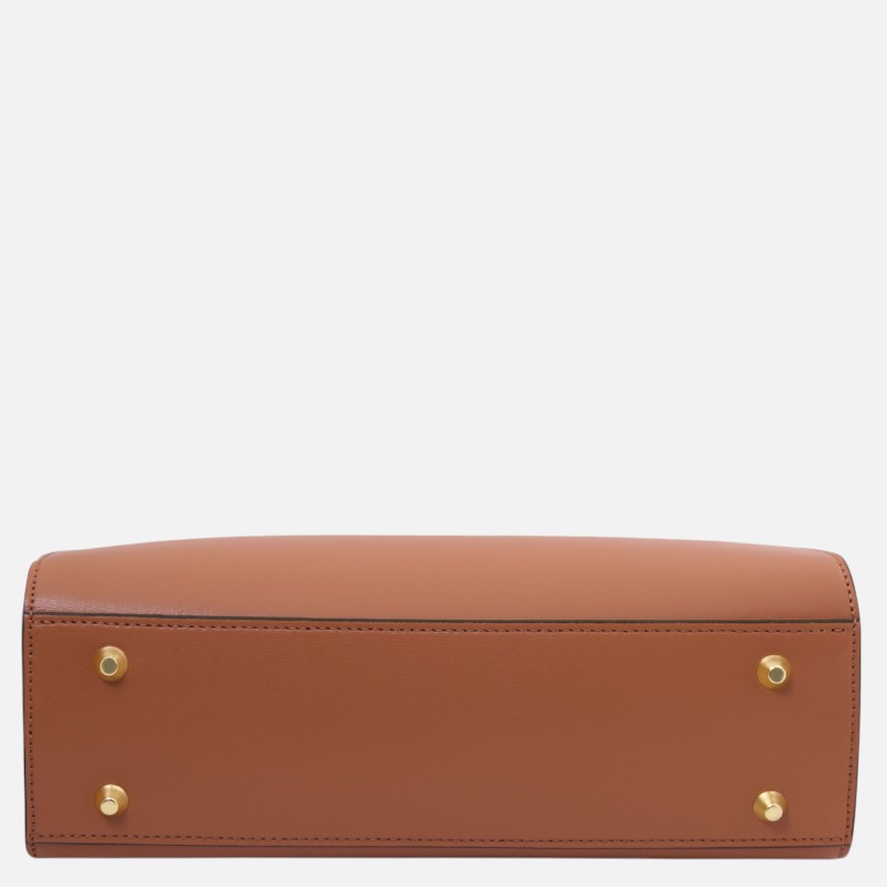 Bottom view of a tan leather handbag with four gold metal studs on the base