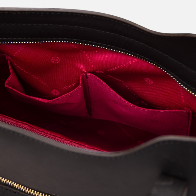 Open black handbag interior with bright red lining and built-in pockets, zipper along the top edge visible.