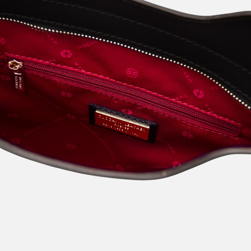 Open handbag interior with red fabric lining, zip pocket, and metal brand tag visible on the lining plate.