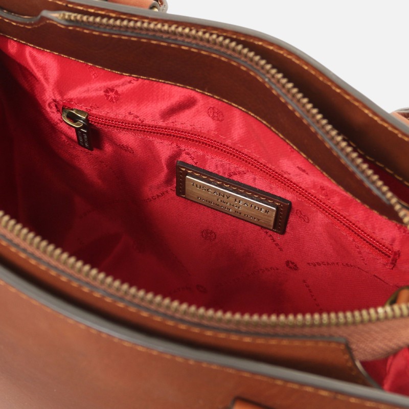 Inside view of a brown leather bag with red lining and a 'Tuscan Leather' brand label.