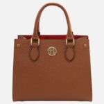 Brown pebbled leather handbag with two handles and gold hardware, red interior visible at top edge, logo disk on front.