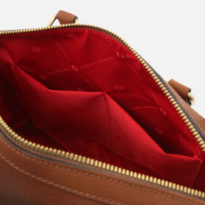 Open brown leather handbag showing red interior lining with two slip pockets.