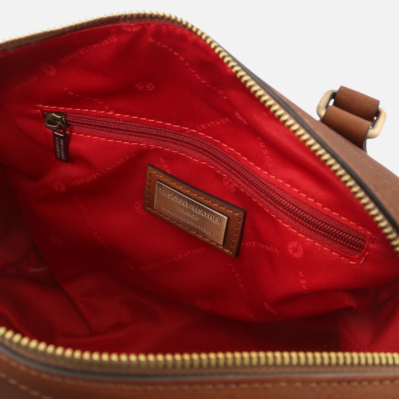 Inside of a brown leather bag showing a red fabric lining, a zip pocket, and a leather brand patch reading 'TUSCANY LEATHER, MADE IN ITALY'