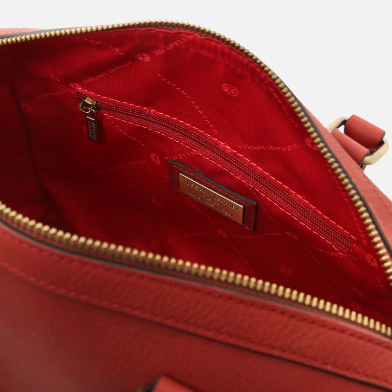 Red leather handbag interior featuring a zip pocket and a metal brand tag reading Tucano Leather.