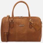 Tan leather duffel bag with two top handles, a detachable shoulder strap, and stitched detailing; has luggage tags attached.