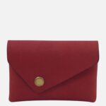 Red envelope-style clutch purse with a brass snap closure on a red surface.