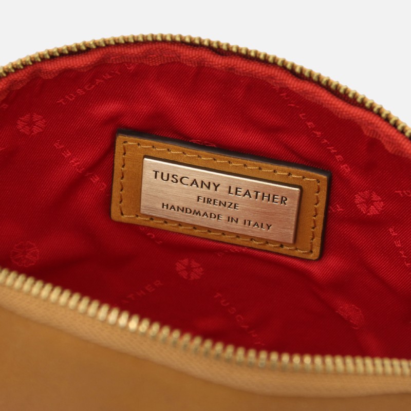 Inside of a tan leather bag with a red lining and a metal brand plate reading 'TUSCANY LEATHER' 'FIRENZE' 'HANDMADE IN ITALY'