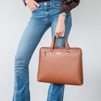 Black rectangular briefcase with dual top handles, a detachable wide shoulder strap, and silver hardware on a white background.